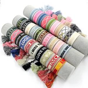 Close-up of colorful woven friendship bracelets with VIBES and LUCKY embroidery on a display