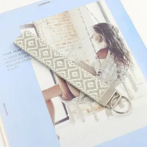 Detalle de llavero trenzado gris y blanco con cierre de metal plateado sobre un libro