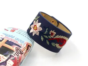 Détail du bracelet large en cuir PU bleu marine avec broderie florale et bouton pression