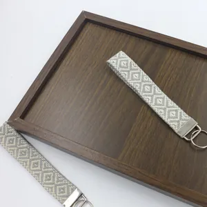 Vista detallada del llavero de pulsera tejida con patrones geométricos grises y blancos