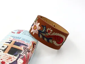 Détail de la broderie florale sur un bracelet large en cuir PU marron avec bouton-pression