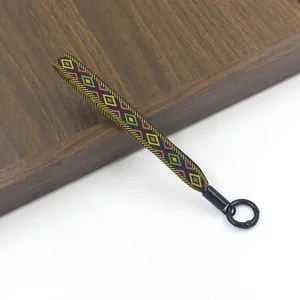 Detail van de etnisch geweven polsband met geometrische patronen en zwarte metalen ring