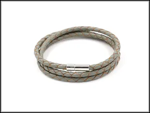 Macro-detail van de drievoudige grijze lederen gevlochten armband met zilveren magneetsluiting