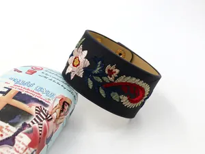 Détail de manchette large en cuir PU noir avec broderie florale colorée et boutons dorés