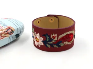 Gros plan détaillé sur un bracelet large en cuir PU rouge foncé avec broderie florale colorée