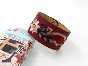 Détail de broderie florale sur un bracelet manchette large en similicuir bordeaux