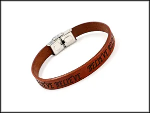 Detail of brown leather strap with laser engraved BELIEVE text and silver metal clasp