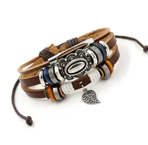Dettaglio del bracciale bohémien in pelle con perline metalliche e ciondolo a foglia