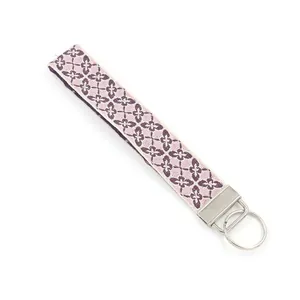 Close-up of ethnic floral embroidery on a purple woven wristlet with silver key ring