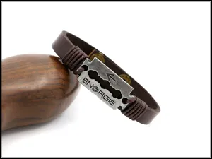 Détail d'un bracelet en cuir marron avec plaque métallique style industriel et logo gravé