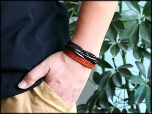 Close-up of multilayer leather bracelet with BELIEVE text on orange band