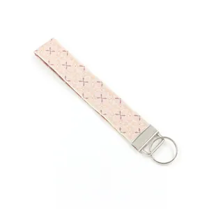 Detail of pink embroidered woven wristlet keychain with geometric floral jacquard pattern