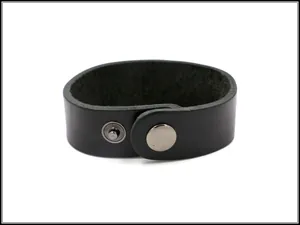 Dettaglio di un bracciale in pelle nera minimalista con chiusura a scatto in metallo
