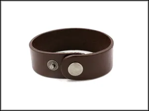 Dettaglio della texture in pelle marrone scuro e bottone a pressione d'argento sul bracciale