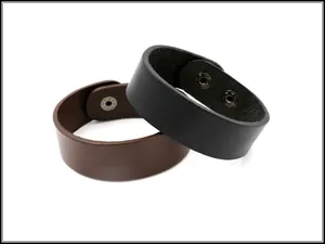 Vista dettagliata di bracciali in pelle nera e marrone con bottoni a pressione in metallo