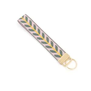 Detail of pink embroidered wristlet keychain with leaf pattern and gold hardware