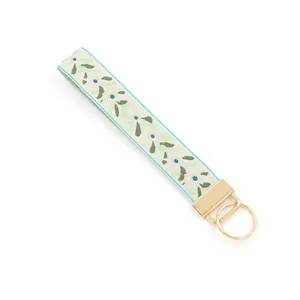 Detail of woven wrist strap with green leaves and blue berries on gold metal ring