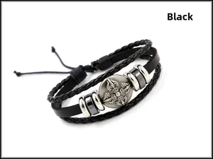 Detail eines mehrlagigen Lederarmbands mit silbernem Schildanhänger und schwarzen Kordeln