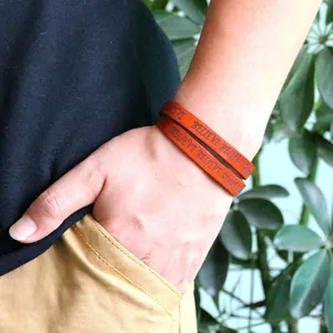 Brown leather wrap bracelet with BELIEVE embossing worn on wrist in a lifestyle setting