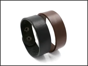Dettaglio di bracciali in pelle nera e marrone con doppia chiusura a bottoni automatici