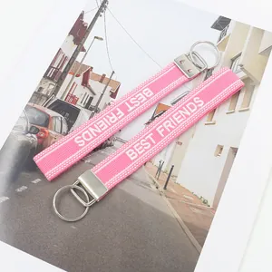 Detail of pink embroidered Best Friends wrist strap keychains with silver metal clasps