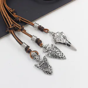Macro detail of Nordic arrow and crow skull pendants on brown leather cord necklaces