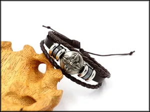 Nahaufnahme des braunen mehrlagigen Lederarmbands mit Kreuzschild-Anhänger