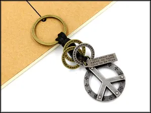 Detail of vintage zinc alloy peace sign charm and braided leather keychain with engraved bar