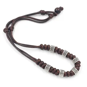 Detail eines dunkelbraunen geflochtenen Seilarmbands mit gravierten Silberperlen und Holz