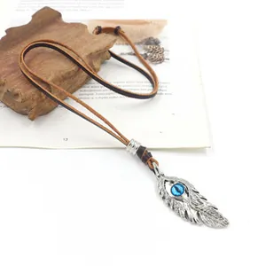 Détail du pendentif plume argentée avec perle bleue et cordon en cuir au style rétro