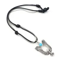 Detalle del colgante de águila plateada con piedra azul y cordón trenzado