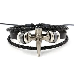 Macro detail of men's multilayer black leather bracelet featuring silver skull cross charm