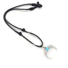 Detalle de un collar de doble capa con colgante de media luna plateada y cuenta turquesa