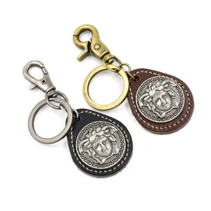 Detail of vintage leather keychains with embossed Medusa head and Greek key metal plates