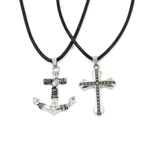 Detail of anchor and cross pendants with black leather cords on white background