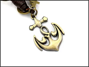Macro detail of bronze anchor and cross pendant on braided brown leather keychain