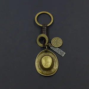 Close-up of vintage bronze cowboy hat pendant with woven leather key ring and engraving