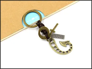 Detail of vintage bronze keychain with leather rope, cross charm, and engraved metal tag
