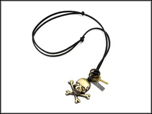 Detail of vintage skull crossbones pendant with engraved metal tag on adjustable cord