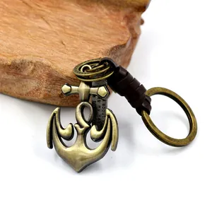 Vintage bronze anchor pendant keychain with brown braided leather strap on wood