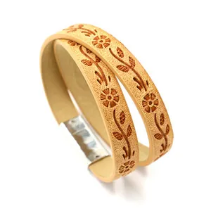 Detail of light brown PU leather wrap bracelet with embossed daisy pattern and silver clasp