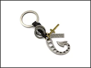 Detail of vintage fishhook keychain with leather cord, cross charm, and engraved metal tag