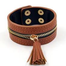 Close-up of brown textured leather cuff with golden zipper, tassel, and snap buttons