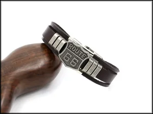 Detailed close-up of brown leather strap featuring a vintage metal Route 66 shield charm