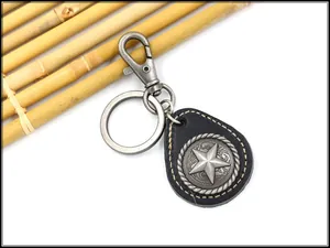 Close-up of vintage leather keychain with a star emblem and ornate metal engraving