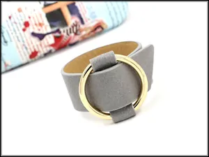Close-up of wide grey leather bracelet with a large polished gold metal ring detail