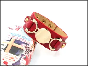 Detail of red textured leather wide bracelet featuring golden buckle and snap closure