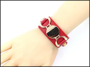 Detail of red litchi texture PU leather wide bracelet with gold metal medallion and studs