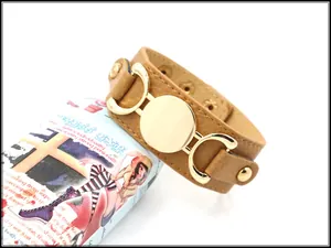 Detail of wide brown faux leather bracelet with gold metal hardware and litchi texture