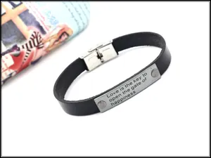 Nahaufnahme von schwarzem Lederarmband mit gravierter Edelstahlplatte und Motivationsspruch